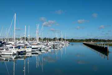 Fototapeta na wymiar boats in the marina at Lymington Hampshire with blue sky and clear reflections in the water