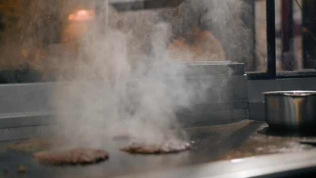 The chef in the kitchen of the restaurant makes cutlets for burgers - smash burger beefsteak