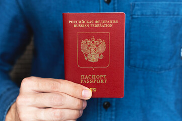close-up of a man's hand in a shirt holding a foreign passport, the concept of preparing for a vacation