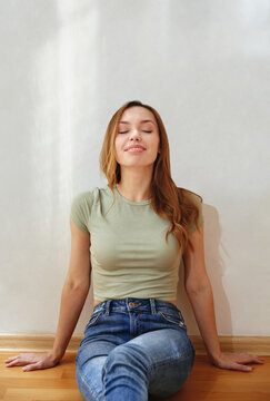 Smiling woman sitting against wall with scribbles