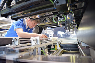 engineer working on a machine for assembly and production of semiconductor boards in an industrial...