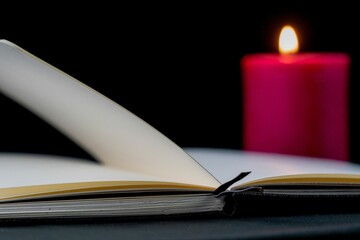 Closeup shot of an open book with a red candle