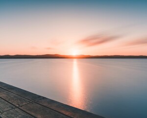 Naklejka na ściany i meble Scenic shot of the pink sunset reflecting the last rays over the still water