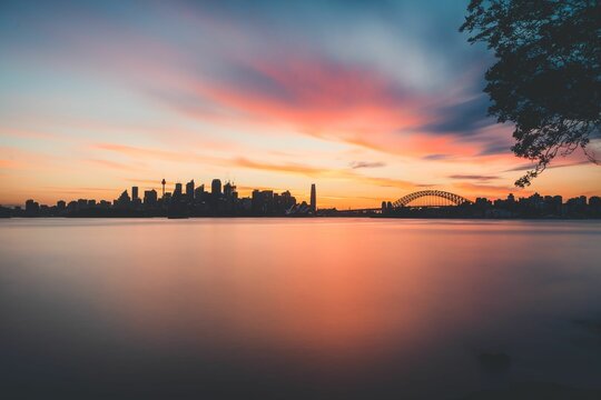 Scenic shot of Port Jackson Bay at sunset and Sydney Harbour Bridge with modern buildings