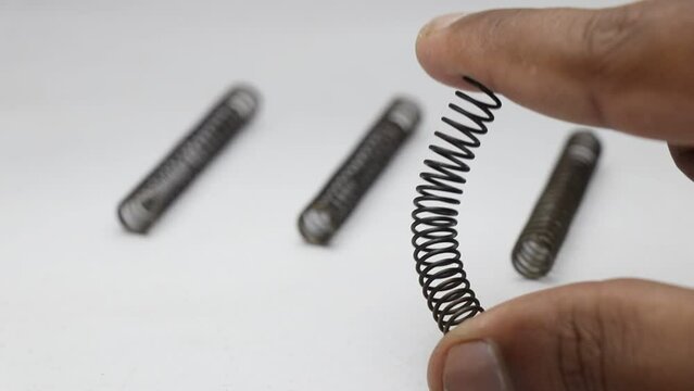 Bending a metal coil spring to test its flexibility. Spare metal springs small in size