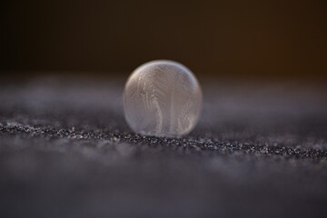 Closeup of the frozen water drop on the grey surface, suitable for backgrounds