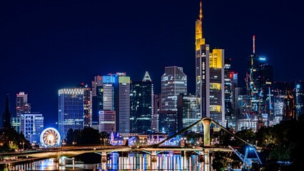 Naklejka premium Beautiful night view of Frankfurt with the buildings' blue lights reflecting in the River Main