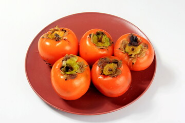 Fresh persimmon fruit on plate. Persimmon fruit Old board background