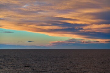 Scenic shot of a calm seascape during an orange sunset with clouds in the sky
