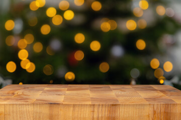 Blank cutting board with the blurred christmas lights in the background. Wooden chopping block and blurred xmas tree.