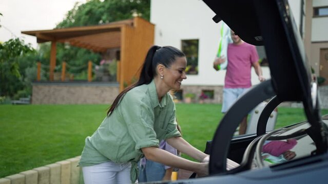 Happy family loading luggage into car before going on summer holiday.
