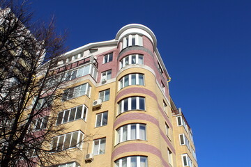 Fototapeta premium Multi-storey building with balconies against the sky on a sunny day.
