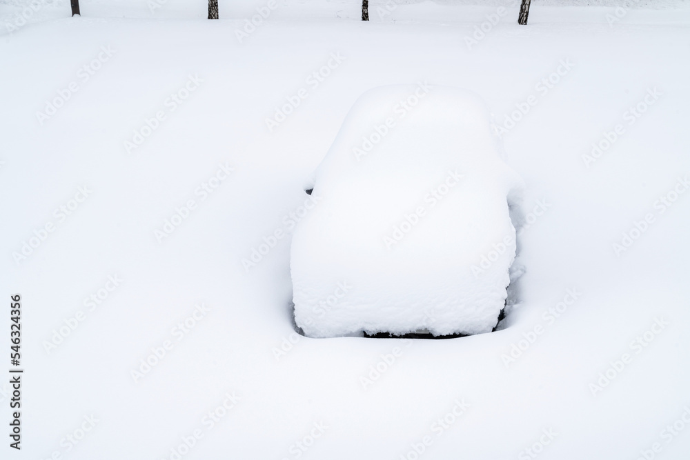 Wall mural Car covered with thick layer of snow. Automobile after snowstorm parked on the street side.