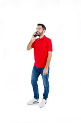 Full-length shot of Handsome man in red shirt keeping a conversation with the mobile phone. Isolated on white background. Studio shot
