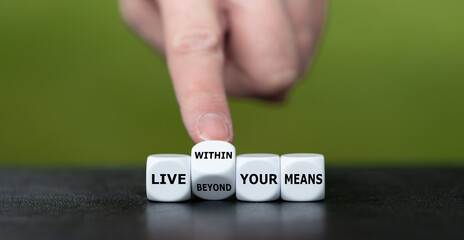 Hand turns dice and changes the expression 'live beyond your means' to 'live within your means'.