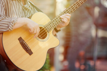 Man playing acoustic bass guitar at outdoor event, close up view to wooden guitar neck. Right...