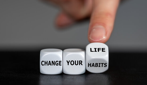 Hand turns dice and changes the slogan 'change your habits' to 'change your life'.