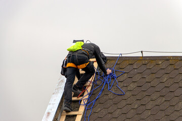 Fototapeta premium Repairman climbs a ladder while repairing the roof
