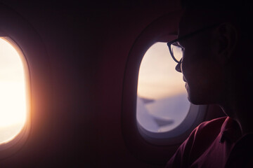Passenger looking out through window of plane during beautiful sunset..