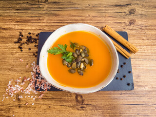 Pumpkin traditional soup with creamy  texture on gray textured background . Top view 