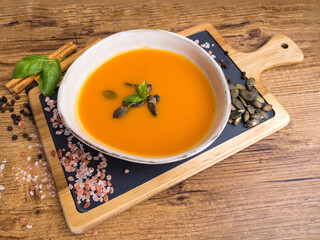 Pumpkin traditional soup with creamy  texture on gray textured background . Top view 