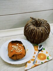 Vertical shot of a pumpkin pie on the white plate with a straw pumpkin decoration