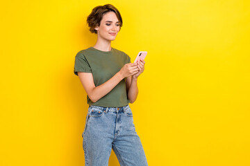 Portrait of gorgeous cheerful woman bob hairdo dressed khaki t-shirt hold phone talk by video call isolated on yellow color background