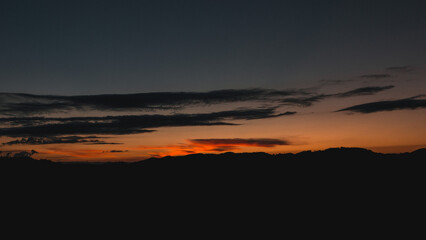Sky after sunset with mountains as silhouette. silhouette of the black forest mountains after sunset with a few clouds in the summer. idyllic natural scene