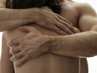 A woman in the arms of a man. Beautiful male hands on a woman's back. Close-up on a white background. Photo without a face.
