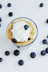 Vertical Closeup of a blueberry dessert in a small bowl on white surface