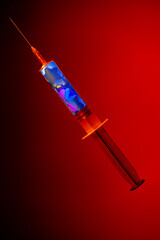Disposable syringe with needle filled with liquid and blue stars of tinsel sequin. Dose of drug on...