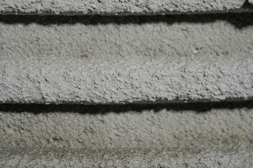 Fresh concrete tehture with patterns of notched trowel. Macro shot of grey surface cement putty on wall with horizontal lines or stripes. Tile installation. Repair work, finishing, decor.