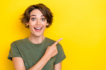 Portrait of positive cheerful pretty woman with bob hairdo dressed khaki t-shirt directing empty space isolated on yellow color background