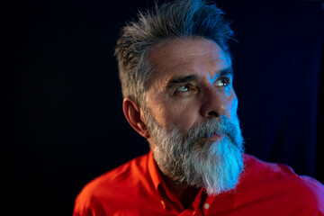 Neon light studio close-up portrait of serious man model with mustaches and beard