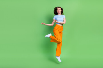 Fototapeta na wymiar Full size photo of sportive active girl jump good mood empty space isolated on green color background