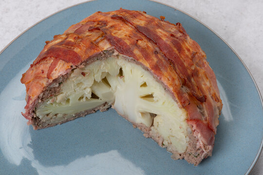 Anschnitt einer Blumenkohlbombe. Blumenkohl umh&uuml;llt von Hackfleisch und Speck