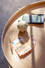 Vertical view from above of cash money, wad of bills, coins and calculator for invesment concept at home in the living room