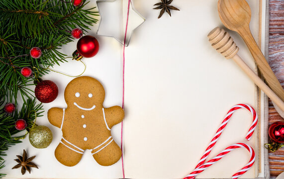 Book For Recipes, Christmas Decor And Gingerbread Man On The Wooden Table. Christmas Baking. Close-up. Top View. Copy Space.