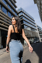 Smiling tattooed woman walking on urban street with sunshine in Prague.