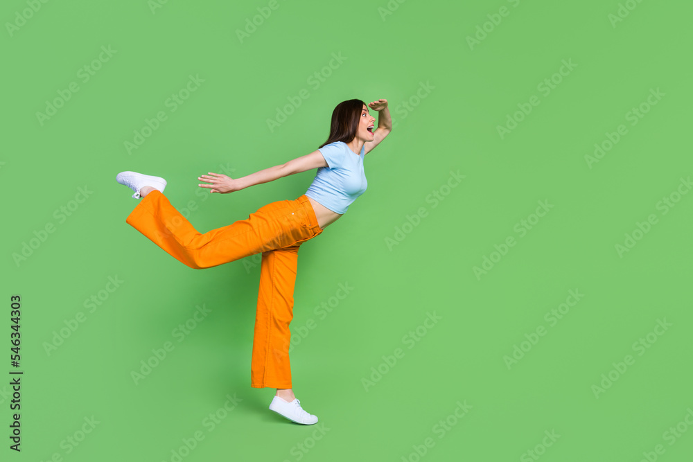 Sticker Full body profile portrait of astonished cheerful lady stand one leg hand touch forehead look empty space isolated on green color background