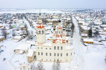 Panorama of a small city in the depths of Russia from a height. Orthodox churches and traditional old wooden houses, Totma in the Vologda region and a winter view of the city