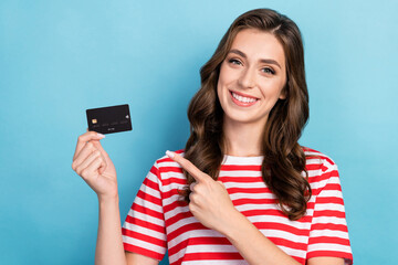 Fototapeta premium Photo of cute positive girl dressed red t-shirt smiling pointing finger credit card isolated blue color background