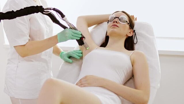 Cosmetologist does laser hair removal of the armpits, laser procedure at beauty studio or clinic. Body epilation treatment and skin care concept.	