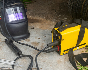 a chameleon welding mask and a welding machine lie near the car being repaired