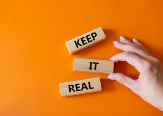 Keep it real symbol. Concept word Keep it real on wooden blocks. Businessman hand. Beautiful orange...