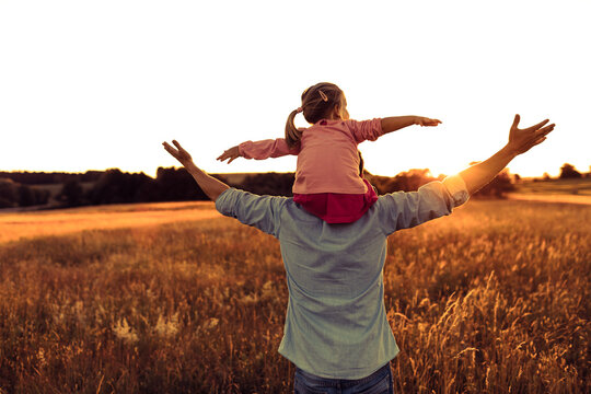 Father and daughter little child in the field at sunset feeling happy and free . Fatherhood, family lifestyle concept.  