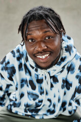 Vertical closeup portrait of young black man wearing hoodie and smiling at camera