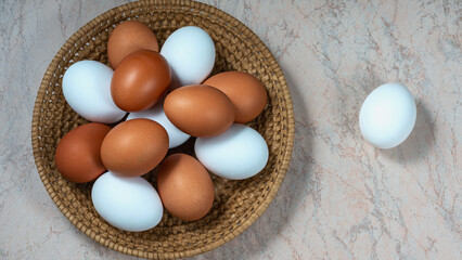 several fresh chicken eggs in a straw basket on a wooden background. Healthy eating concept.