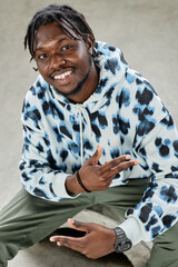 Vertical portrait of young black man wearing hoodie and smiling at camera