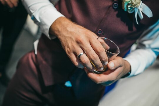 Closeup shot of the groom holding a glass cup during the wedding reception